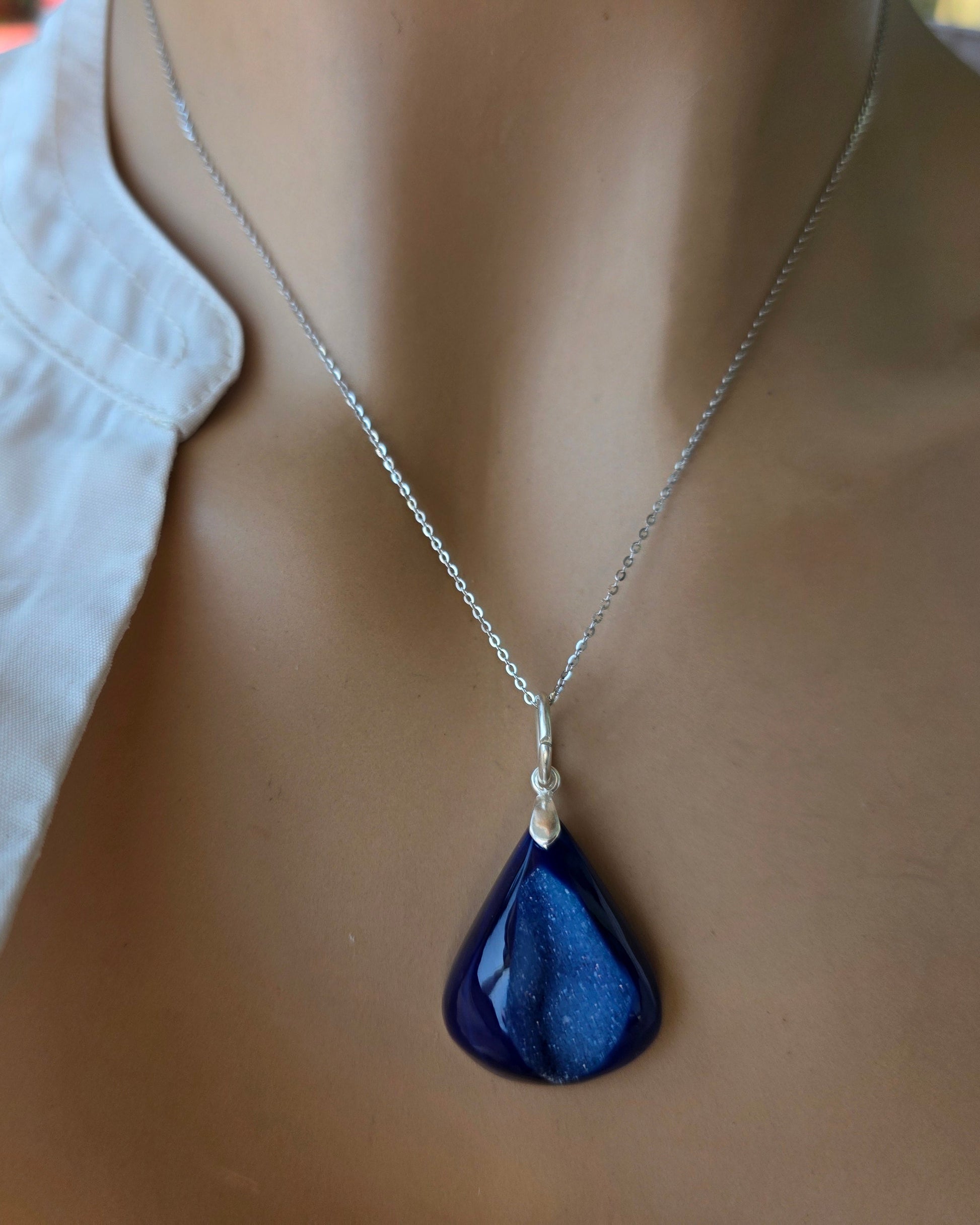 Mannequin wearing a white shirt with a blue teardrop pendant necklace.