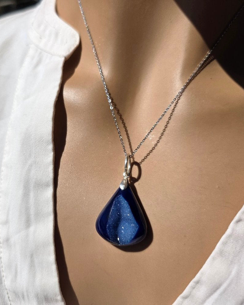 Mannequin wearing a white shirt with a blue teardrop pendant necklace.