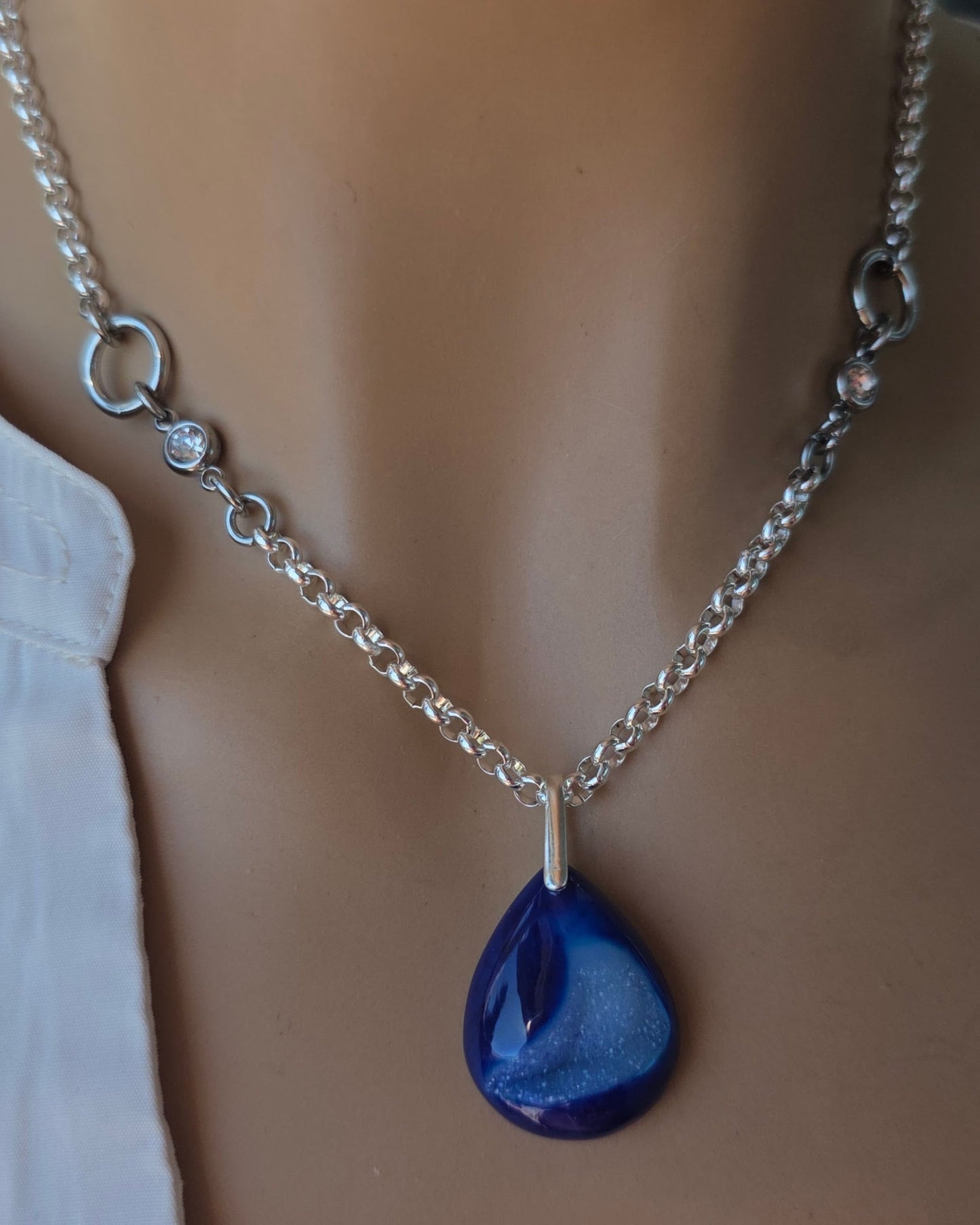 Necklace with a blue teardrop pendant on a mannequin wearing a white shirt.