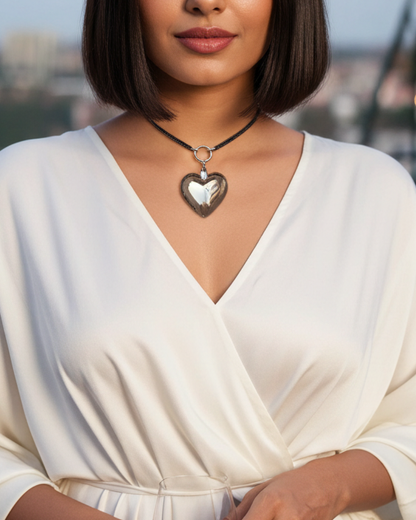 Woman in a white dress with a heart-shaped necklace standing outdoors.