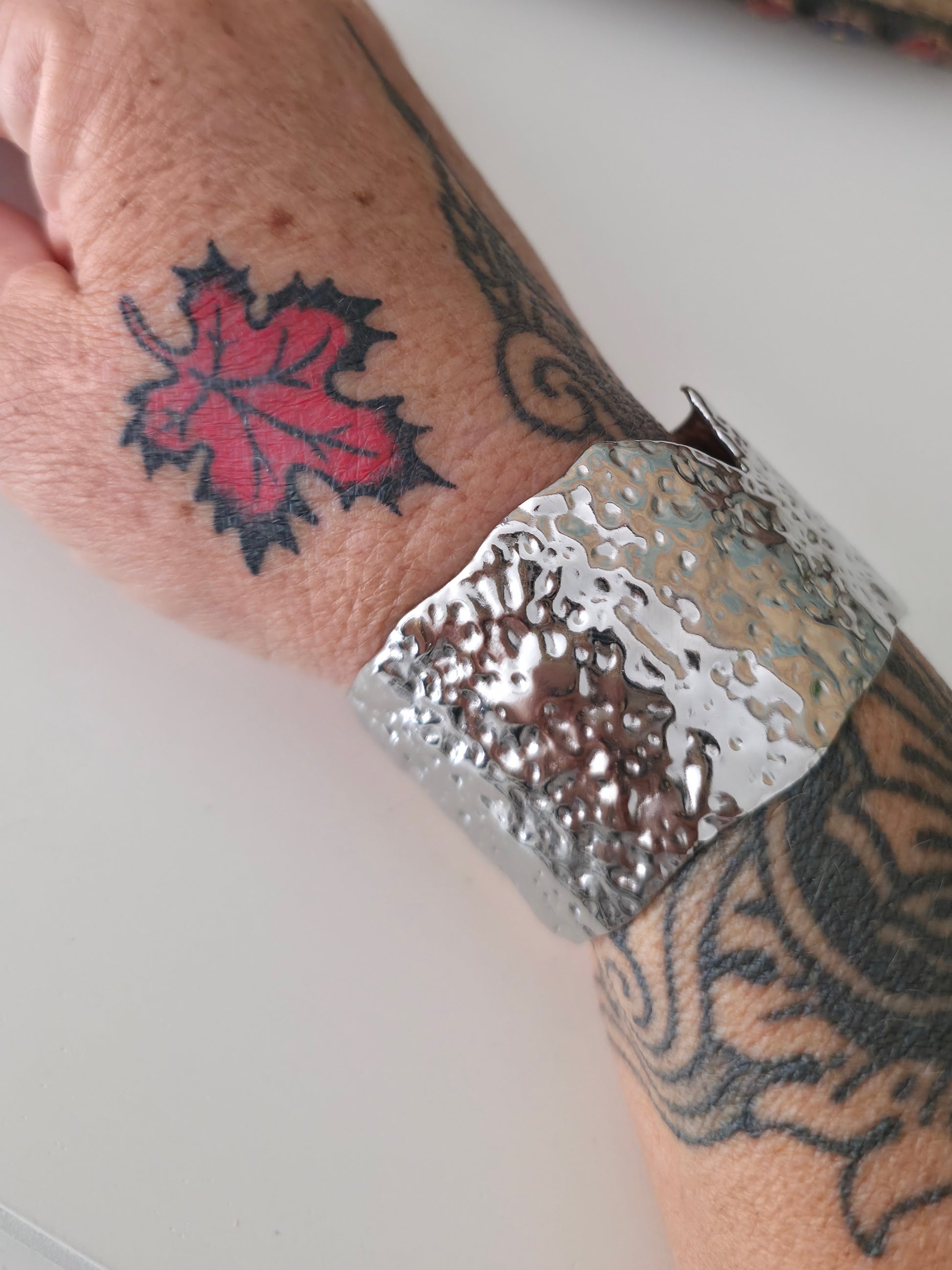 Silver cuff bracelet on a wrist with tattoos
