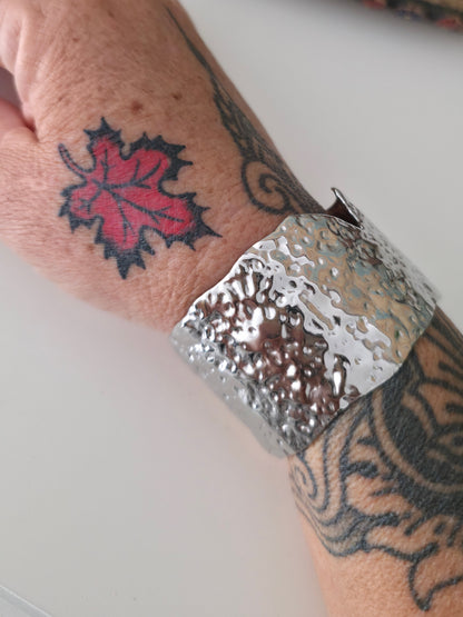 Silver cuff bracelet on a wrist with tattoos