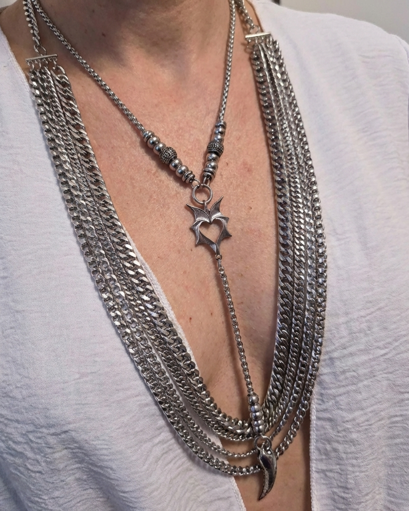 Close-up of a person wearing multiple silver chain necklaces with a star pendant.