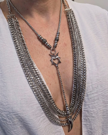 Close-up of a person wearing multiple silver chain necklaces with a star pendant.