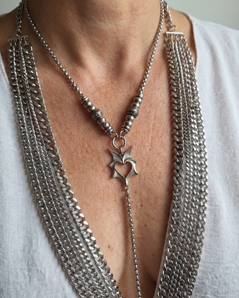 Close-up of a person wearing a long, layered silver necklace with a star pendant.