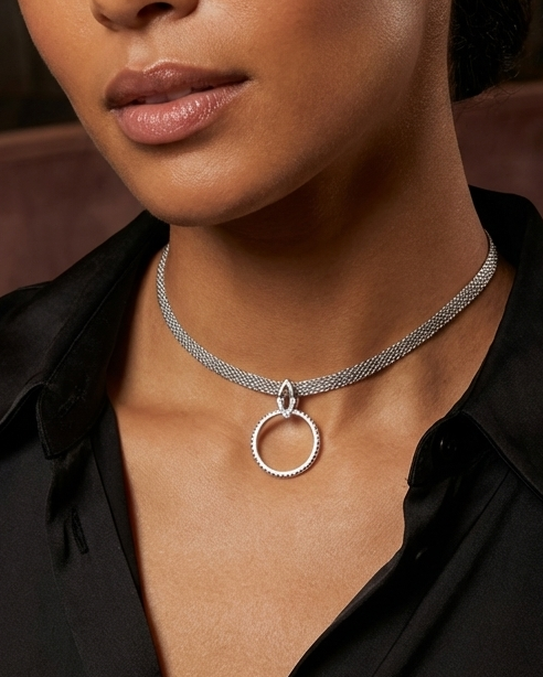 Woman wearing a silver necklace in an indoor setting with soft lighting