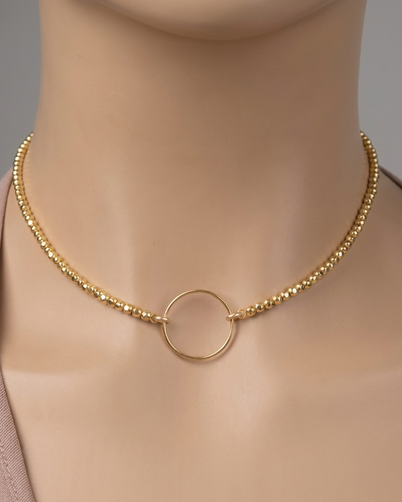 Gold necklace with a circular pendant on a mannequin against a neutral background