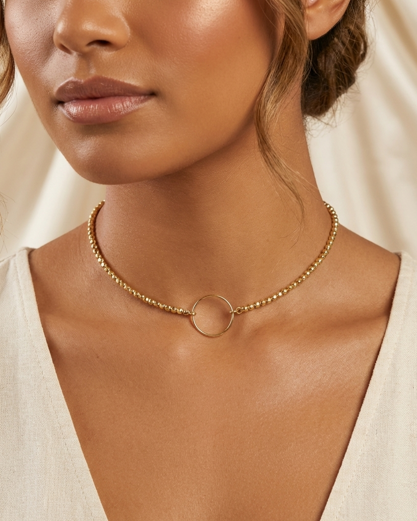 Close-up of a woman wearing a gold necklace with a plain background