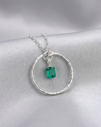 Silver necklace with a green gemstone pendant on a gray background