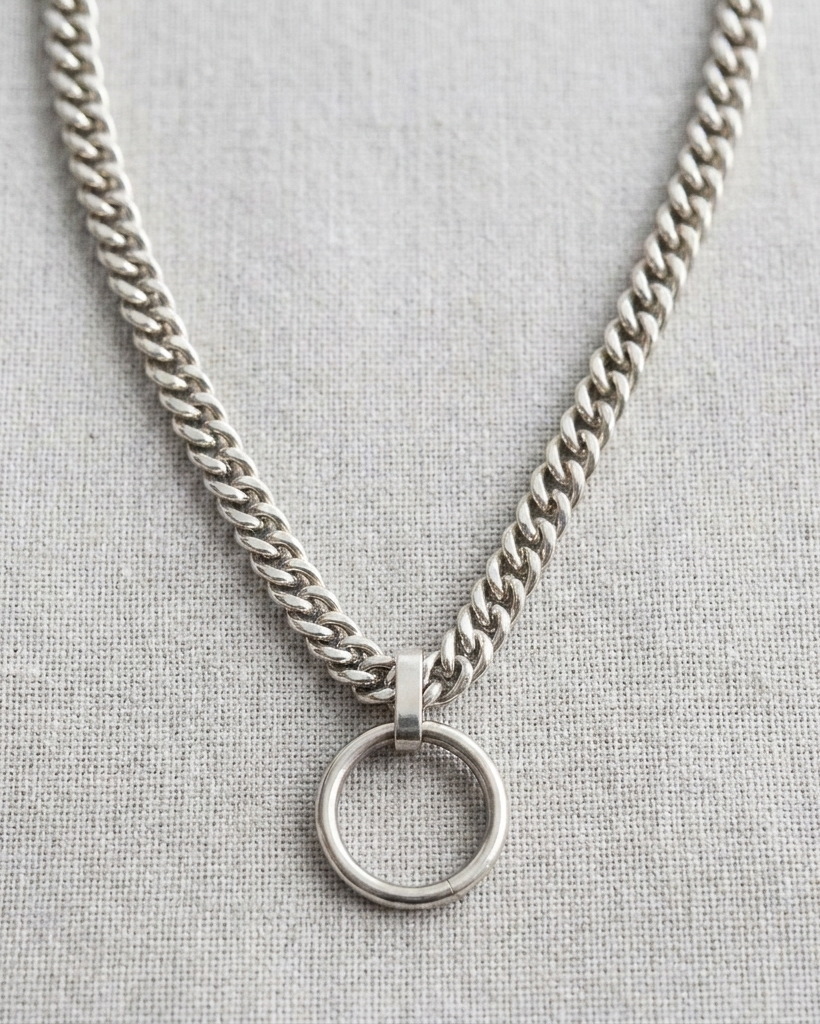 Silver chain necklace with a round pendant on a light gray background