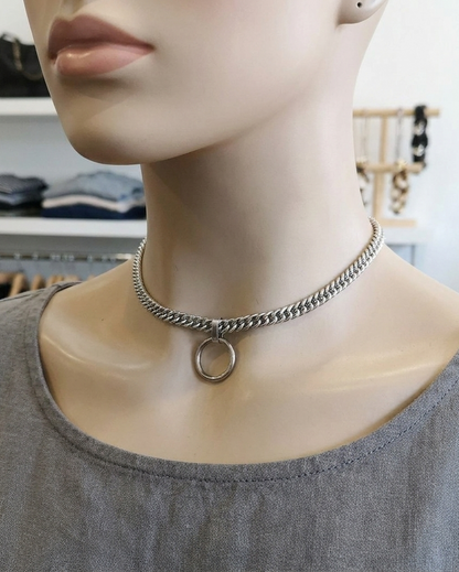 Mannequin wearing a silver chain necklace with a circular pendant in a store setting.