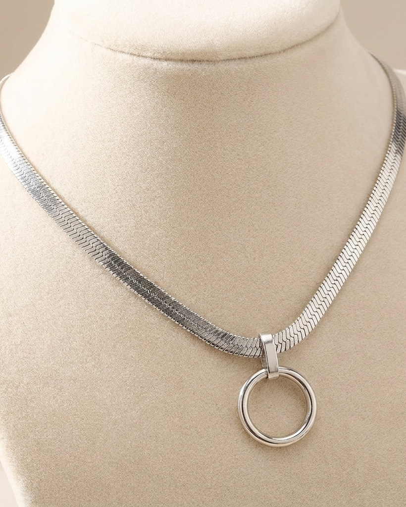 Silver necklace with a circular pendant on a mannequin bust.