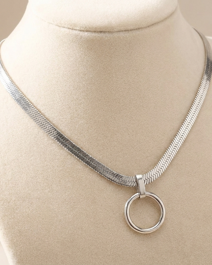 Silver necklace with a circular pendant on a mannequin bust.