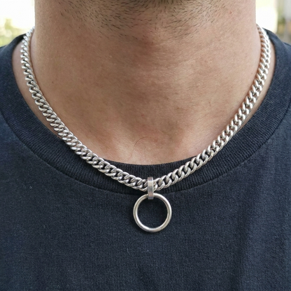 Silver chain necklace with a round pendant on a person wearing a dark blue shirt.