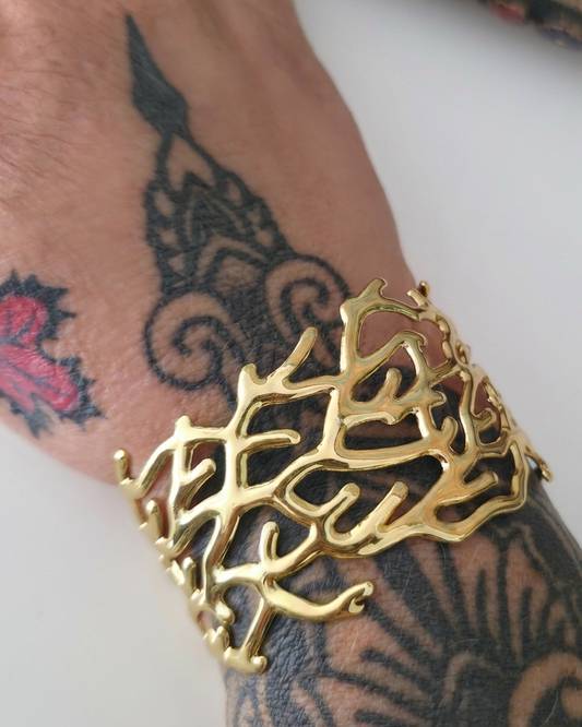 Gold bracelet on a wrist with tattoos