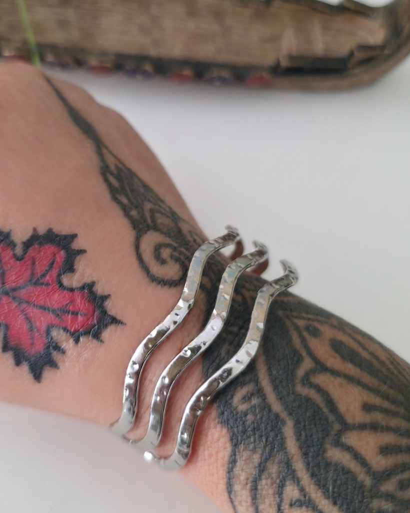 Silver cuff bracelet on a wrist with tattoos