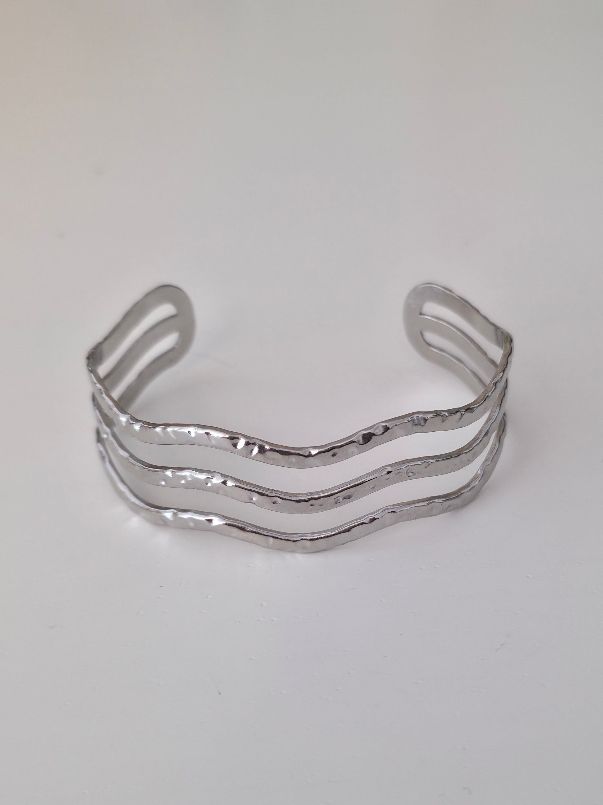 Silver bracelet with wavy design on a white background