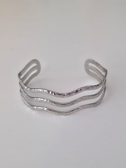 Silver bracelet with wavy design on a white background