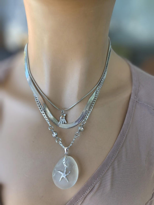 Photo of a genuine ocean-tumbled sea glass pendant in stainless steel bezel on a stainless steel chain, handmade coastal jewelry inspired by Norse goddess style.