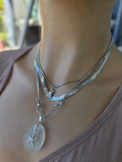 Photo of a genuine ocean-tumbled sea glass pendant in stainless steel bezel on a stainless steel chain, handmade coastal jewelry inspired by Norse goddess style.