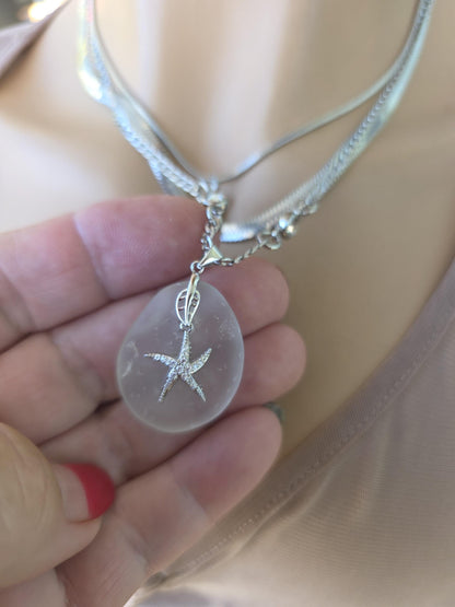 Photo of a genuine ocean-tumbled sea glass pendant in stainless steel bezel on a stainless steel chain, handmade coastal jewelry inspired by Norse goddess style.