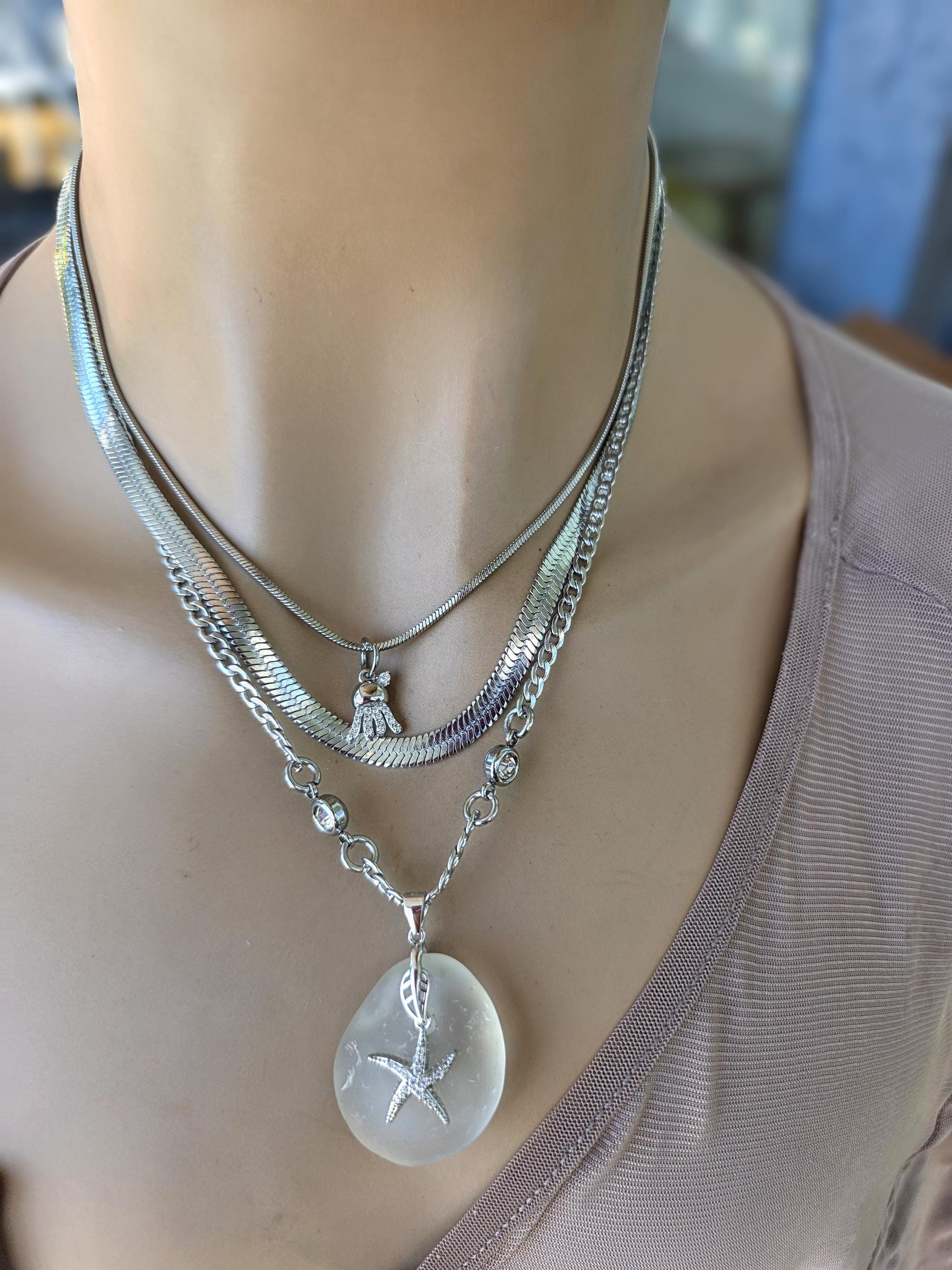 Photo of a genuine ocean-tumbled sea glass pendant in stainless steel bezel on a stainless steel chain, handmade coastal jewelry inspired by Norse goddess style.
