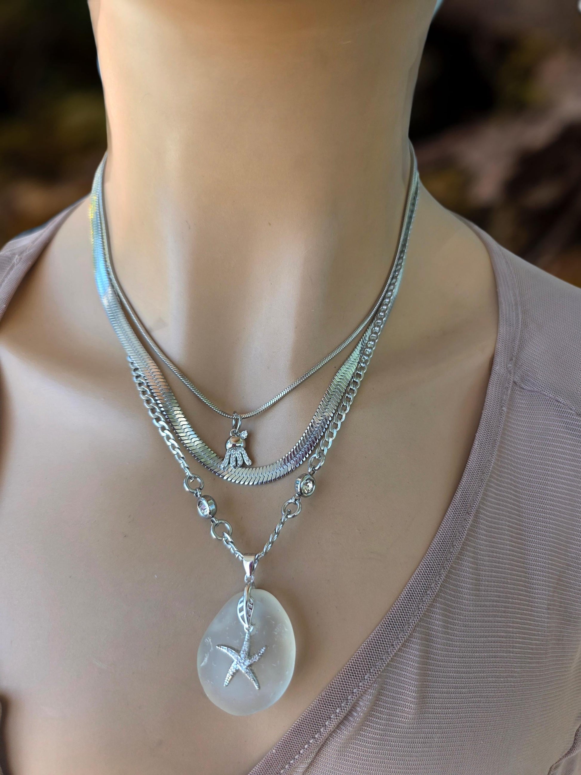 Photo of a genuine ocean-tumbled sea glass pendant in stainless steel bezel on a stainless steel chain, handmade coastal jewelry inspired by Norse goddess style.