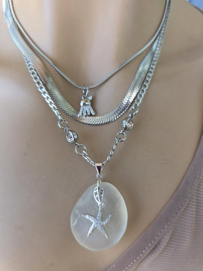 Photo of a genuine ocean-tumbled sea glass pendant in stainless steel bezel on a stainless steel chain, handmade coastal jewelry inspired by Norse goddess style.