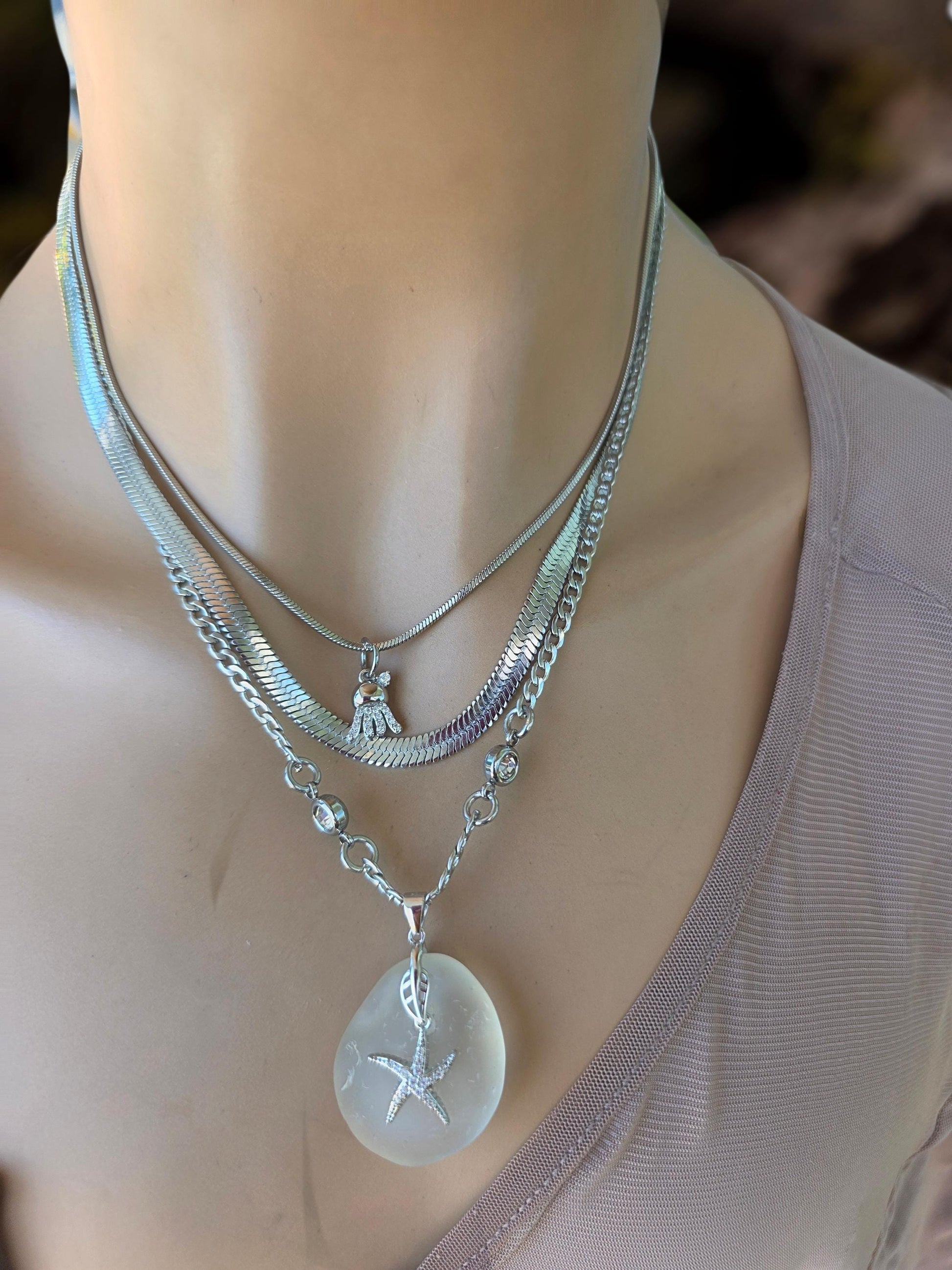 Photo of a genuine ocean-tumbled sea glass pendant in stainless steel bezel on a stainless steel chain, handmade coastal jewelry inspired by Norse goddess style.