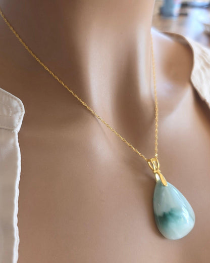 Mannequin wearing a gold necklace with a green teardrop pendant.