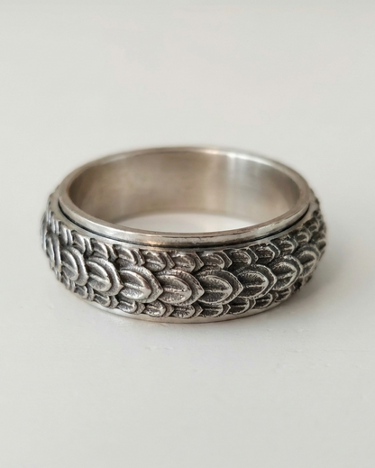 Silver ring with intricate design on a light gray background