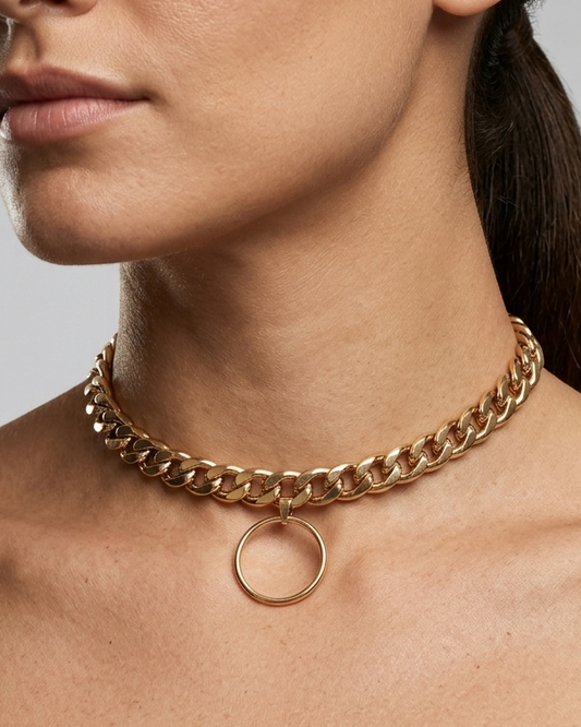 Gold chain necklace worn by a person on a gray background