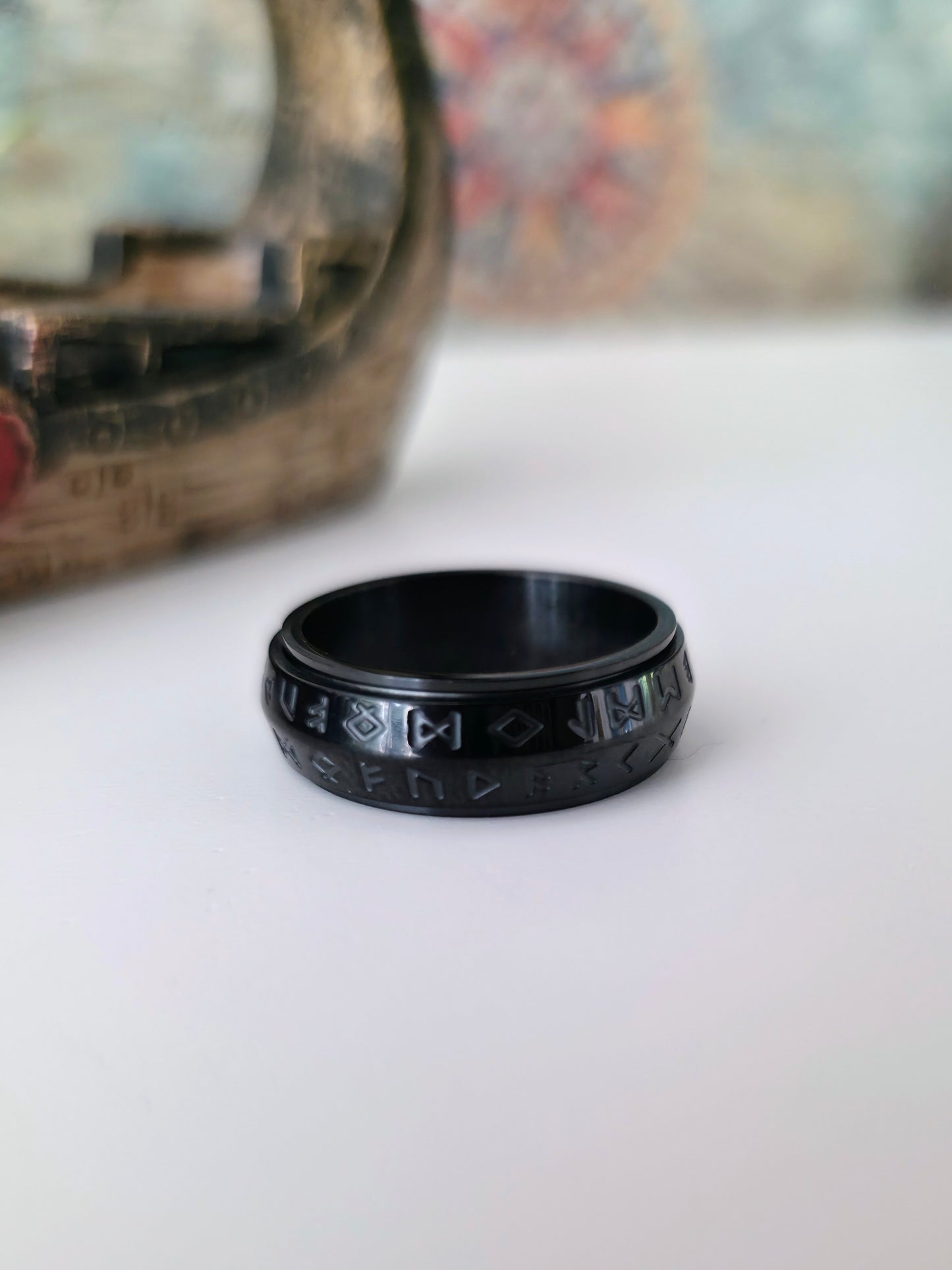 Black ring with engraved design on a white surface