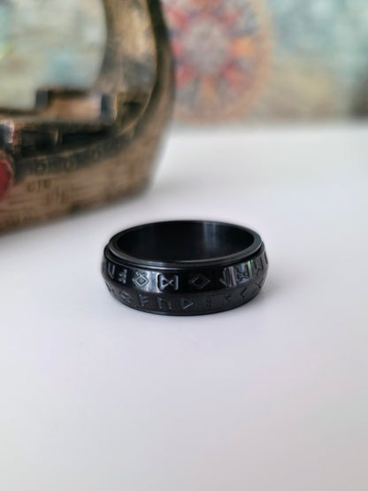 Black ring with engraved design on a white surface