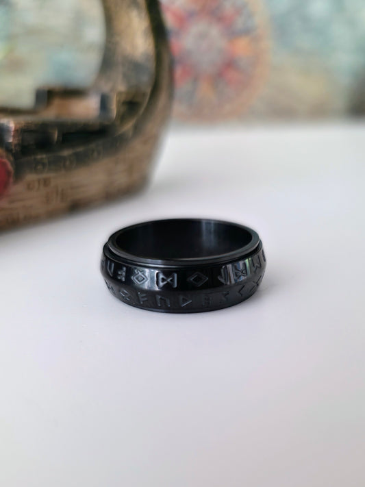 Black ring with engraved design on a white surface