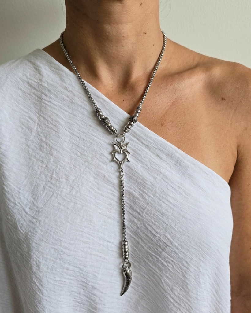 Person wearing a silver necklace with star and feather pendant on a plain background